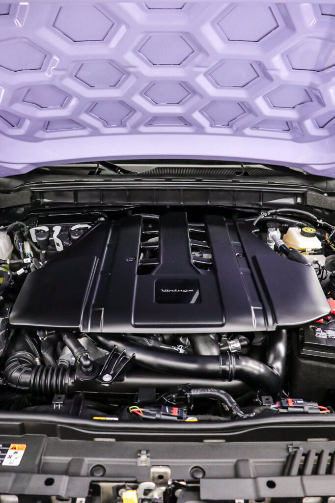 High-performance car engine under a purple geometric-patterned hood, showcasing modern automotive design and powerful engineering details. Perfect for showcasing vintage modern vehicle aesthetics and advanced engine technology.